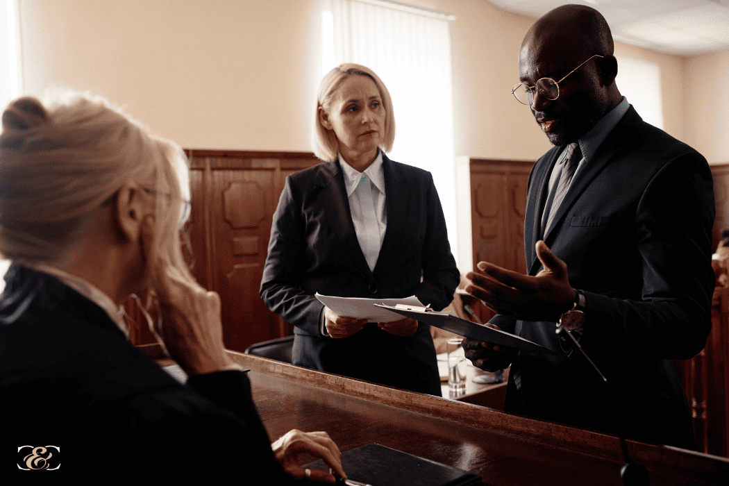 Defense and prosecution sides of court case standing in front of judge.
