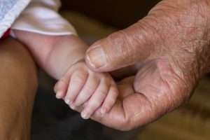 Life events that trigger an estate plan update | crowl crowl Close Up of an Old Man's hand holding a baby's hand.