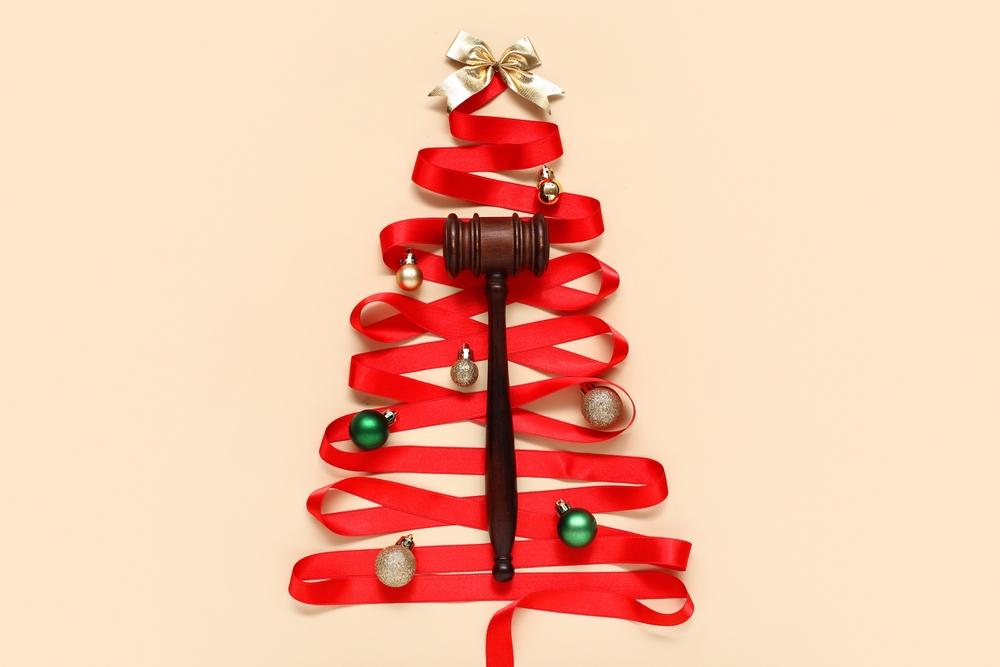 Christmas tree made of red ribbon, judge gavel and decorations on color background