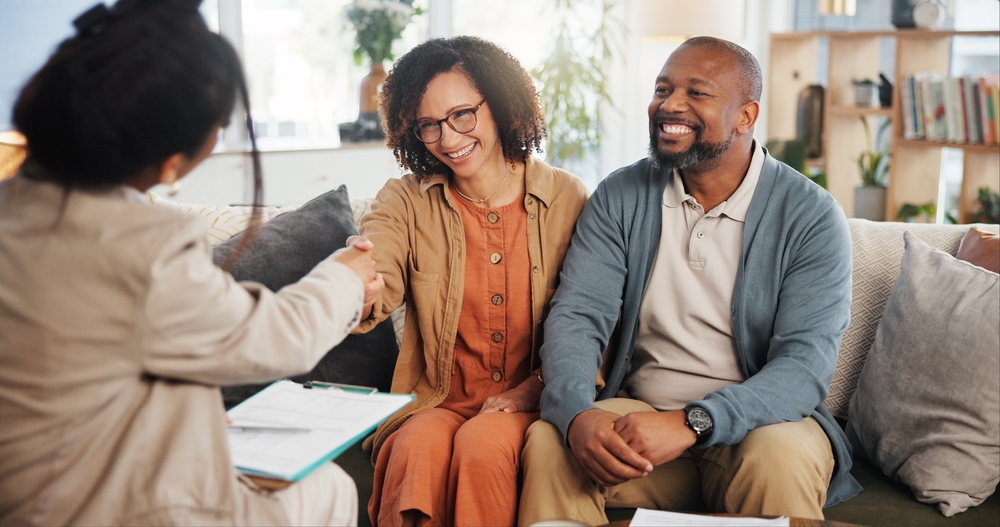 Financial advisor shaking hands with a mature couple during an estate planning consultation meeting.