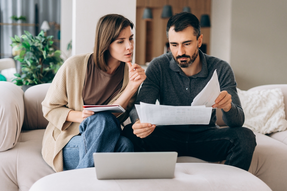 Couple reviewing financial documents together while discussing household planning and paperwork