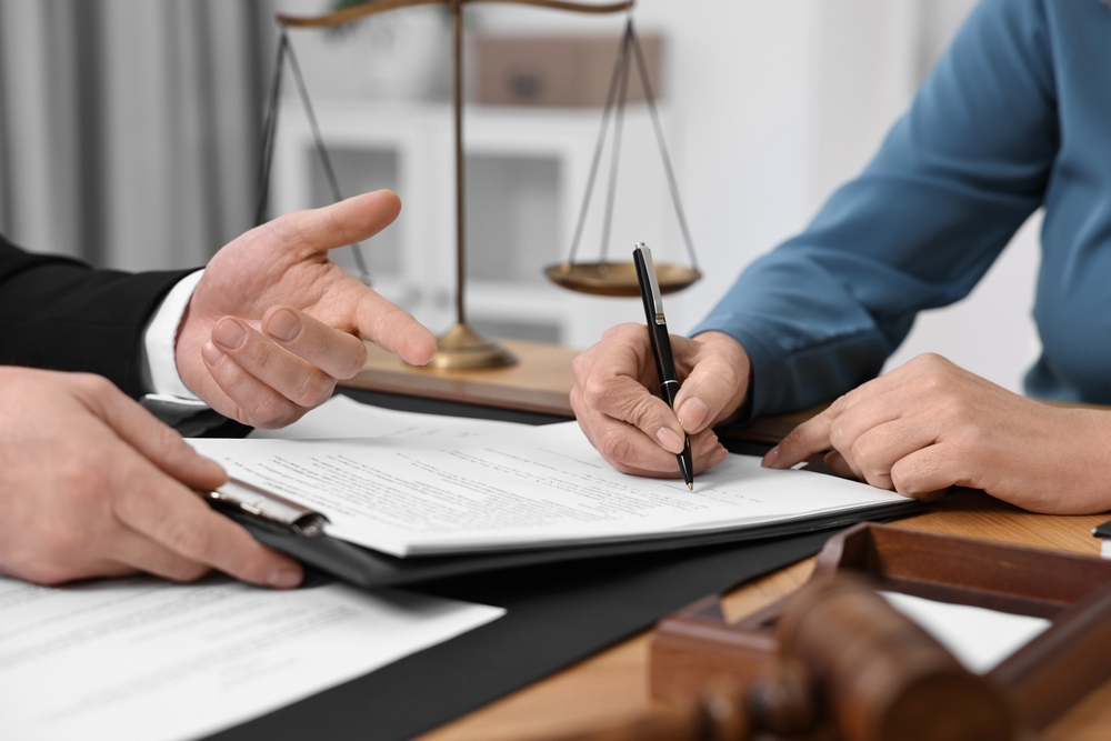 SeniorWomanSigningDocumentInLawyersOfficeCloseup Senior woman signing a durable power of attorney document during a meeting with her attorney.